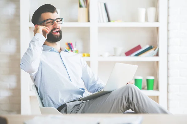 Uomo con computer portatile al telefono — Foto Stock