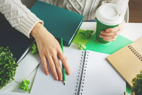 Female with coffee writing in notepad