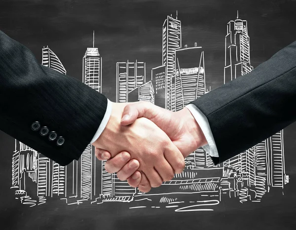 Close up of handshake infront of blackboard with city sketch. Partnership concept — Stock Photo, Image