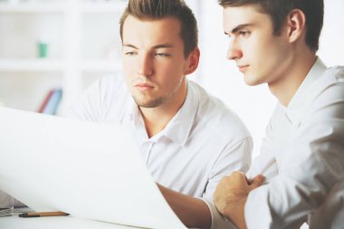 Ekip çalışması kavramı. İki çekici genç beyaz erkek modern ofis evrak işi yapıyor