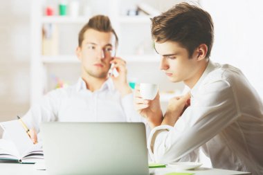 Projede çalışan ve cep telefonu üzerinde konuşurken işyerinde çekici beyaz erkek portresi. Ekip çalışması kavramı