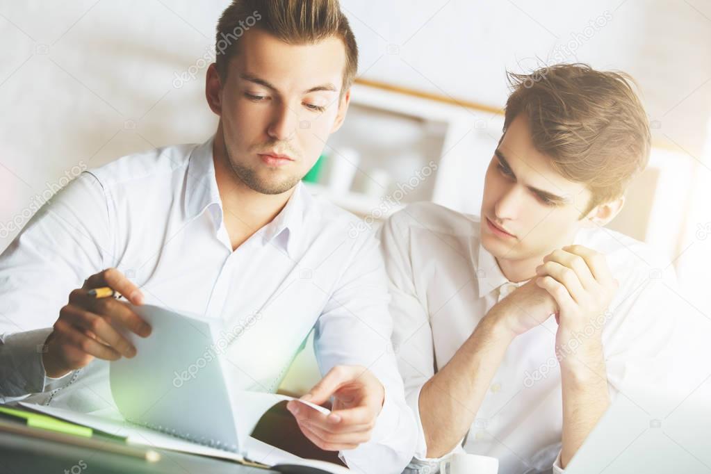 Teamwork concept. Portrait of two attractive european males working on project in modern office.