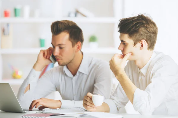 Retrato de homens europeus bonitos no local de trabalho trabalhando no projeto e falando no telefone celular. Conceito de trabalho em equipa — Fotografia de Stock