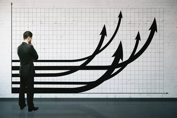 Uomo d'affari con frecce grafico sul muro — Foto Stock