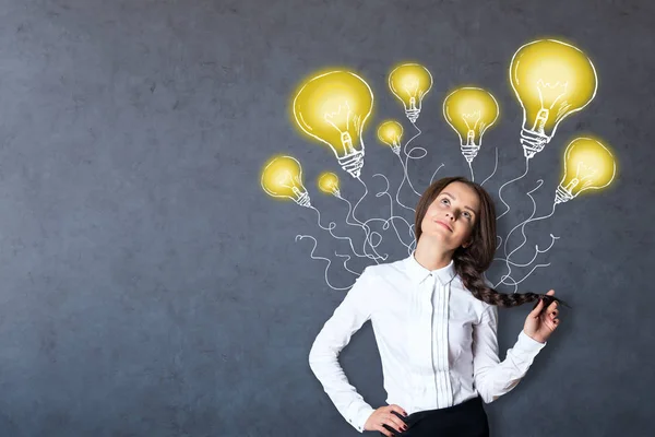 Rêve fille caucasienne sur fond de béton avec des dessins de lampe créatifs. Concept d'idées — Photo