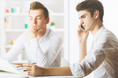 Projede çalışan ve cep telefonu üzerinde konuşurken işyerinde çekici beyaz erkek portresi. Ekip çalışması kavramı