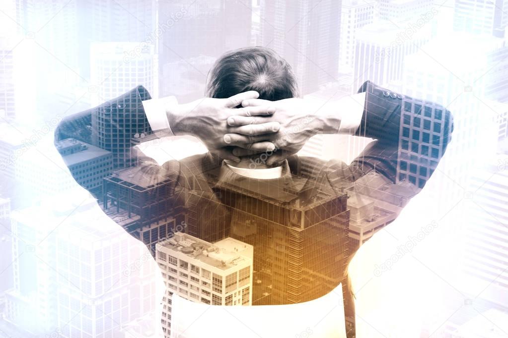 Back view of relaxing businessman on city background. Success concept. Double exposure