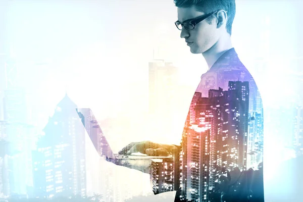 Joven hombre de negocios usando portátil en el fondo de la ciudad de noche. Concepto de comunicación. Doble exposición — Foto de Stock