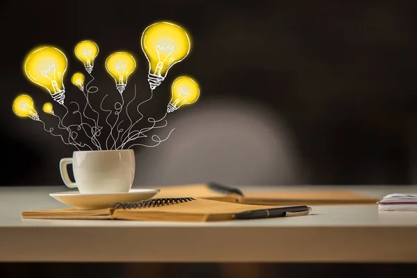 Immagine creativa del desktop dell'ufficio con palloncini di lampada disegnati astratti in tazza di caffè. Idea concetto — Foto Stock