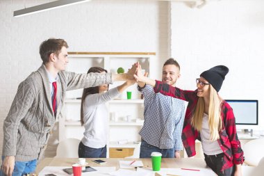 Neşeli genç çocuklar ve kız modern ofis Merhaba-çakmak içinde her diğer grup. Başarı ve ekip çalışması kavramı