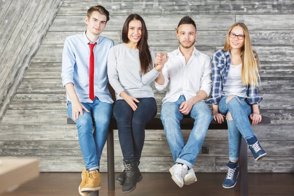 Fyra unga kaukasiska företagare sitter på bord i träinredning och hålla händerna. Lagarbete koncept — Stockfoto