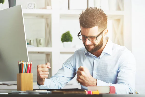 Jovem empresário europeu no local de trabalho com punhos cerrados como sinal de sucesso — Fotografia de Stock