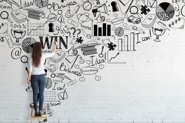 Zadní pohled na mladou ženu stojící na stoličce a kreslení náčrtu kreativní podnikání na cihlovou zeď. Koncepce vedení — Stock fotografie