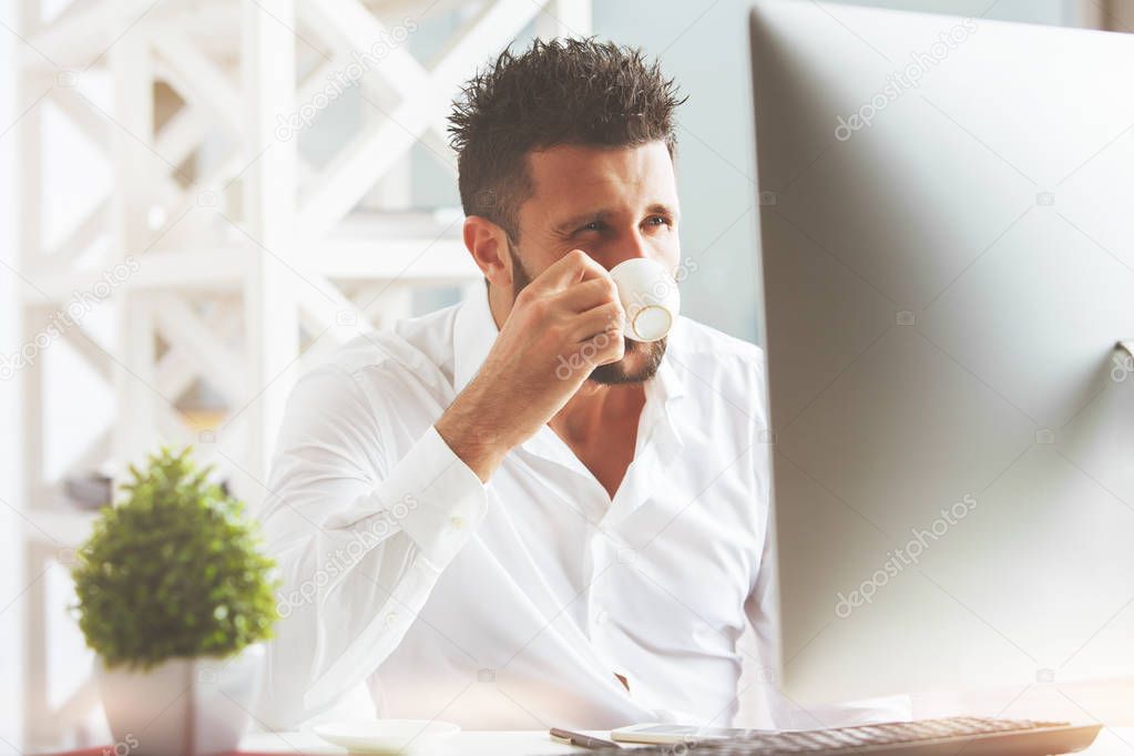 Man with coffee looking at screen