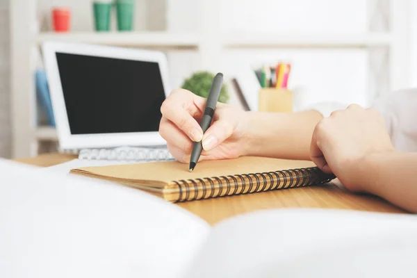 Lady with laptop writing in notepad — Stock Photo, Image