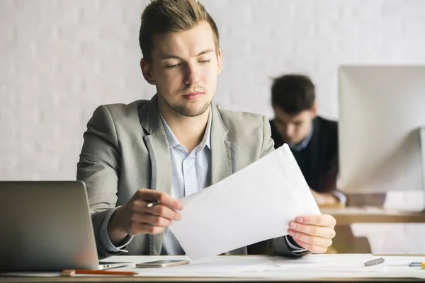 Retrato de un hombre de negocios caucásico guapo trabajando en un proyecto en el lugar de trabajo. Colega borrosa en el fondo — Foto de Stock