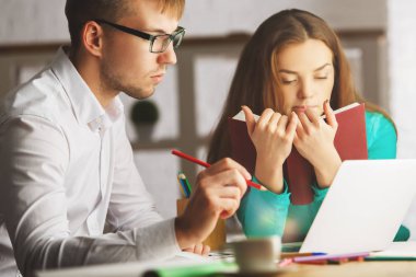 Çekici genç erkek ve dişi dizüstü kullanarak ve modern işyerinde evrak işlerini yapıyor. Proje üzerinde birlikte çalışıyorlar. Ekip çalışması kavramı