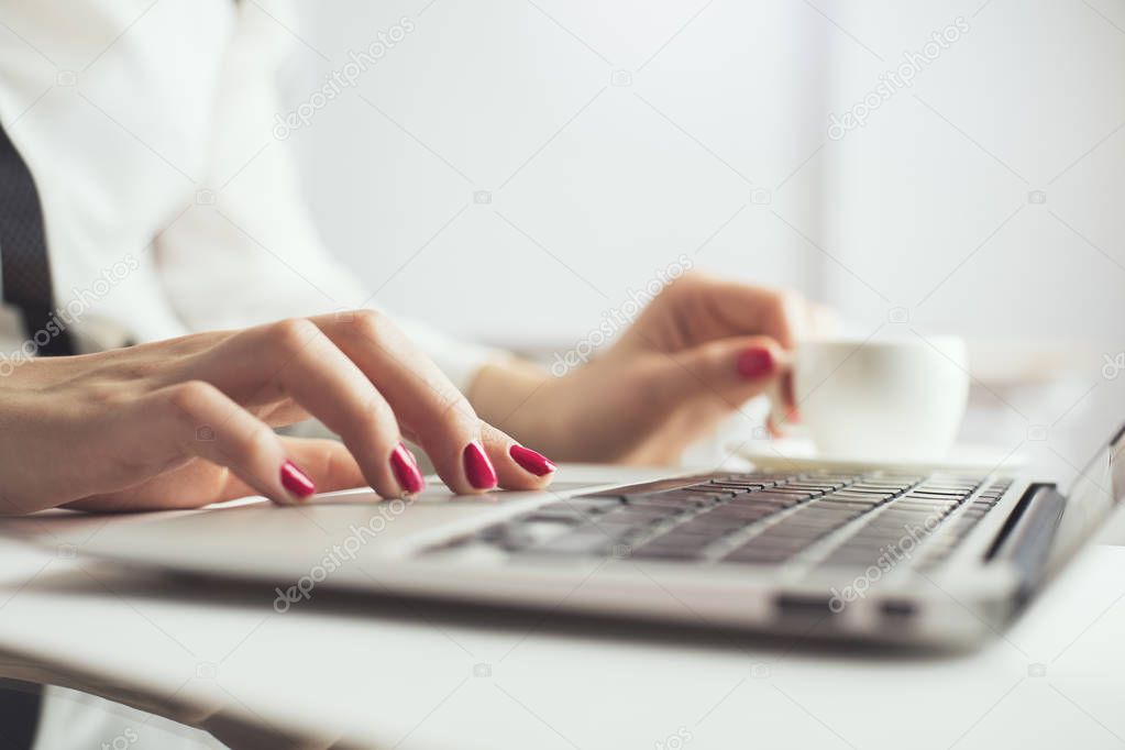 Female drinking coffee, using laptop
