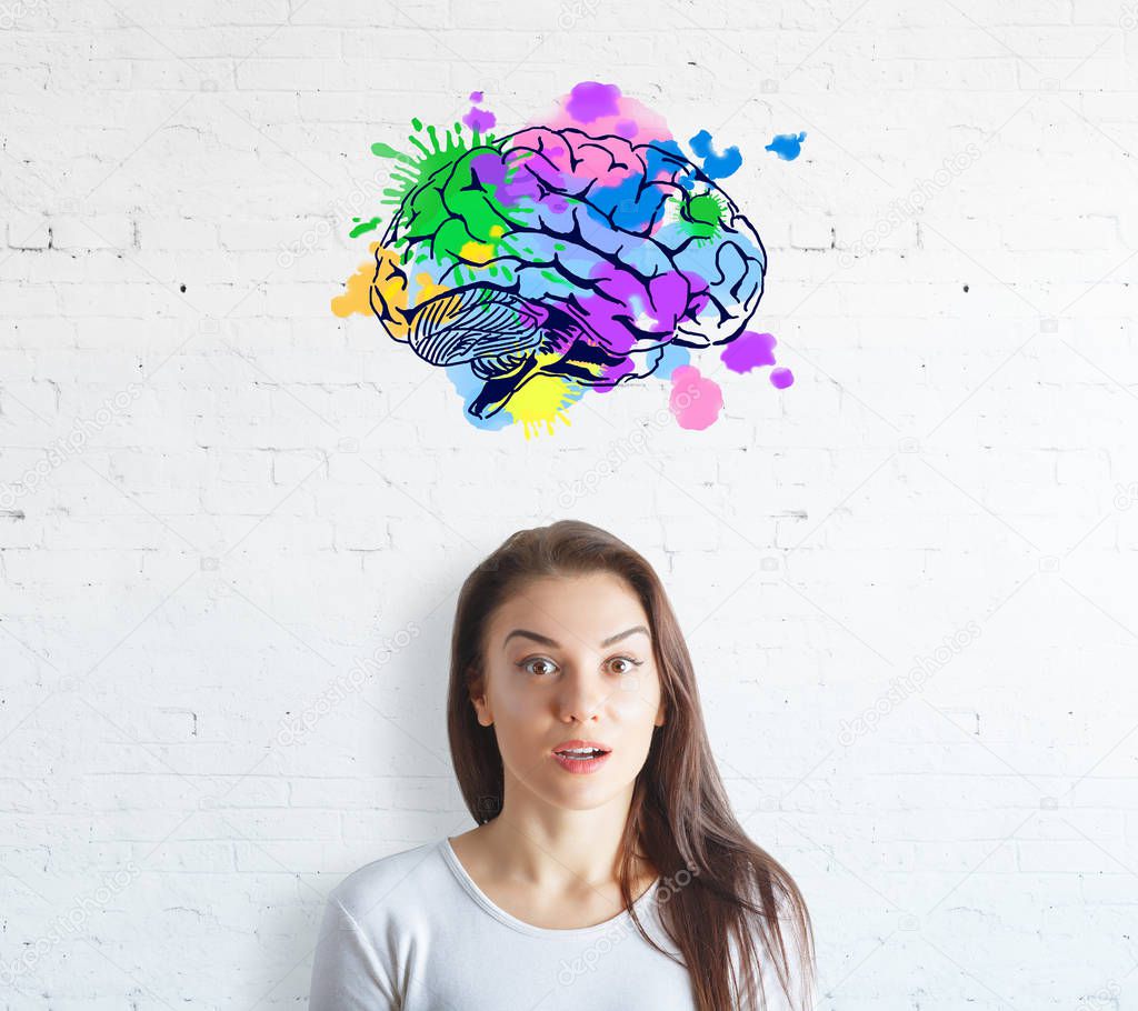 Surprised young woman on white brick background with colorful brain sketch. Creative mind concept