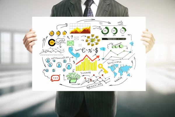 Primer plano de las manos del hombre de negocios sosteniendo cartel con croquis de negocios coloridos en el interior borroso . —  Fotos de Stock