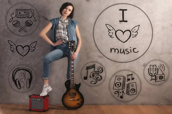 有吸引力的年轻女性，吉他与脚上放大器站在内部与混凝土墙上素描. — 图库照片