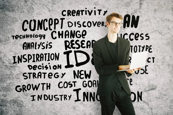 Joven empresario alegre usando portátil sobre fondo concreto con texto . — Foto de Stock