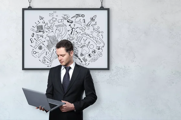 Stilig ung affärsman med laptop på konkreta bakgrund med business skiss i ram. Presentation-konceptet. — Stockfoto