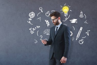 Genç işadamı eğitim çizimler ve ampul beton zemin üzerine Smartphone kullanarak. Bilgi kavramı