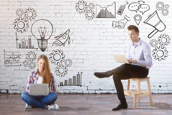 Jovem empresário europeu e mulher usando laptops no interior com desenhos de negócios. Conceito de tecnologia — Fotografia de Stock