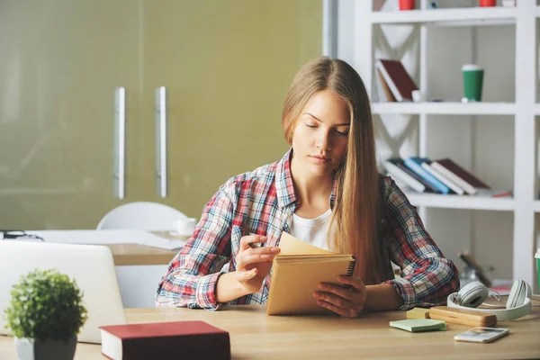 Nachdenkliche Frau schreibt in Notizblock — Stockfoto