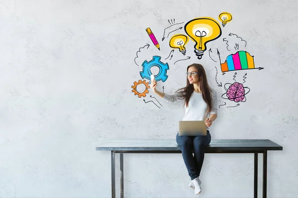 Jonge vrouw zittend op tafel met laptop en nemen selfie met smartphone. Concrete achtergrond met kleurrijke business schets. Prestatie concept — Stockfoto