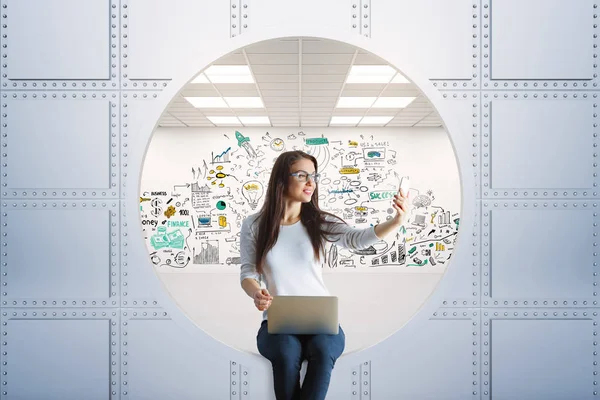 Young businesswoman with laptop taking selfie with smartphone in silver vault. Safety concept. 3D Rendering — Stock Photo, Image