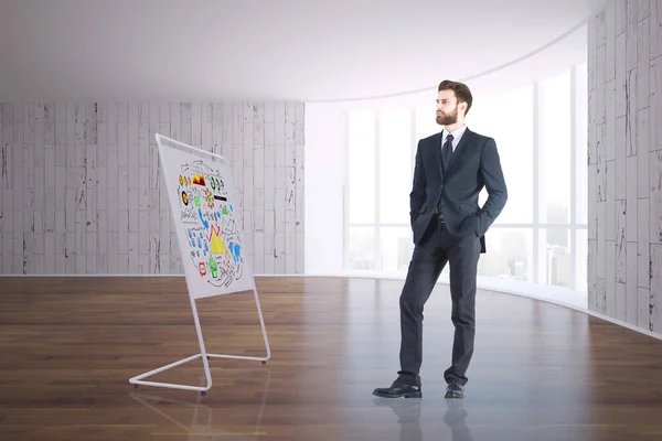 Joven hombre de negocios guapo en el interior limpio mirando el soporte de pizarra blanca con croquis de negocios coloridos. Concepto de taller. Renderizado 3D —  Fotos de Stock