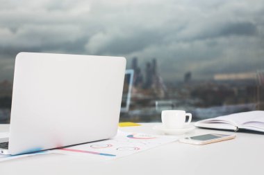 Açık dizüstü, finansal raporlar, smartphone ve kahve fincanı pencere sıkıcı şehir manzaralı yerleştirilen yakın çekim