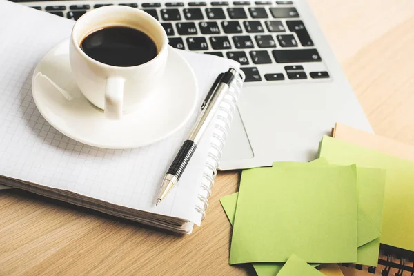 Primo piano del desktop in legno per ufficio con laptop, tazza di caffè, blocco note a spirale e adesivi colorati — Foto Stock