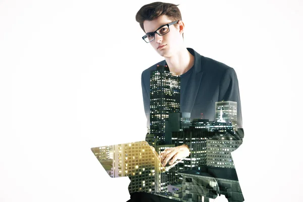 Side view of young man using laptop on abstract city background. — Stock Photo, Image