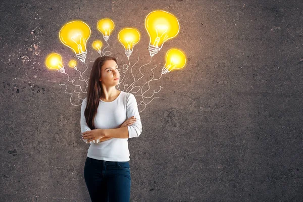 Thoughtful young european woman on concrete background with drawn yellow lamps. Idea concept — Stock Photo, Image