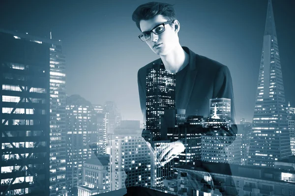 Vista laterale del giovane uomo d'affari che utilizza laptop su sfondo astratto della città . — Foto Stock