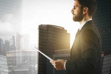Genç işadamı documet güneşli şehir arka planda tutan yan görünüm. İş kavramı