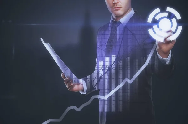 Young european businessman with document in hand pressing digital button. Business charts in the background. Accounting concept — Stock Photo, Image