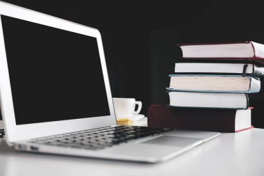 Dizüstü bilgisayar, kahve ve kitaplar