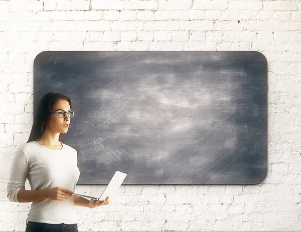Vrouw met laptop naast schoolbord — Stockfoto