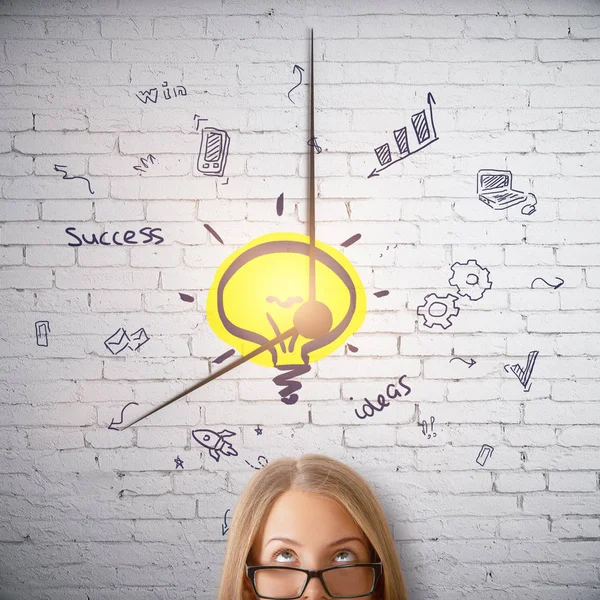 Retrato de mujer bastante caucásica en gafas sobre fondo de ladrillo blanco con reloj creativo de negocios y lámpara dibujada. Concepto de idea — Foto de Stock