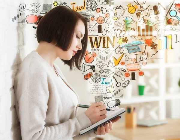 Seitenansicht einer attraktiven jungen Frau, die etwas in einen Notizblock schreibt, während sie im verschwommenen Bürointerieur mit Geschäftsskizze steht. Führungskonzept — Stockfoto