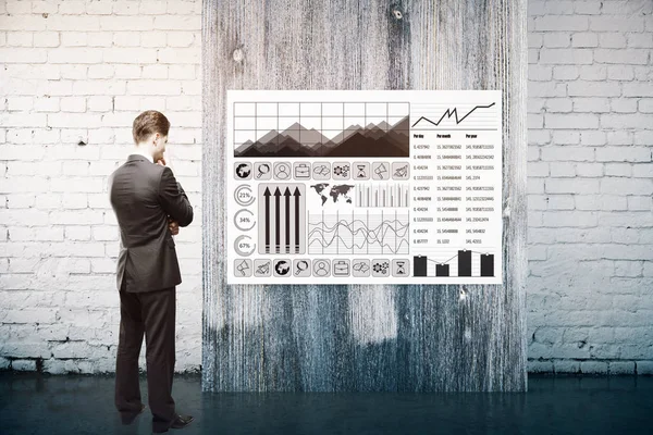 Przemyślane biznesmen w garnitur, patrząc na tablicy z wykresów biznesowych w ceglane wnętrza z drewnianymi panelu. Pojęcie dochodu. renderowania 3D — Zdjęcie stockowe