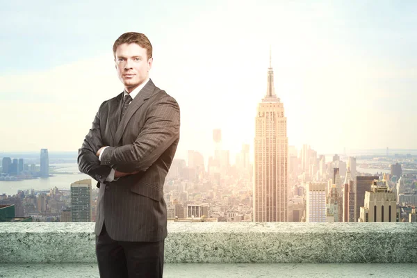 Bel giovane uomo d'affari in piedi sul tetto di cemento con vista sulla città di New York e la luce del sole. Concetto di fiducia — Foto Stock