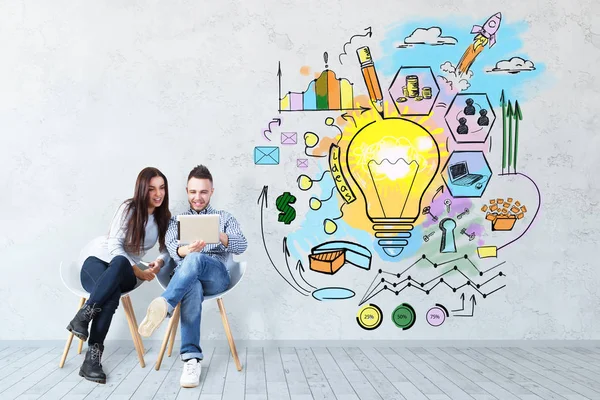 Çekici genç Avrupa adam ve sandalyelere oturan ve kullanarak kadın iş kroki beton zemin üzerine tablet. Teknoloji kavramı