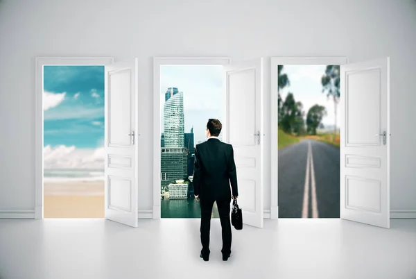 Vista trasera de joven hombre de negocios en interior de hormigón con tres puertas abiertas y diferentes vistas. Concepto de éxito. Renderizado 3D — Foto de Stock