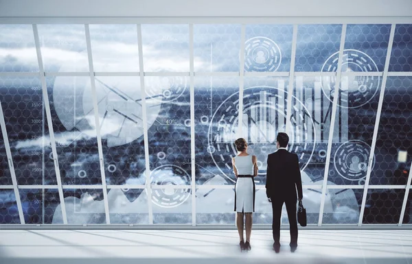 Vista posteriore di giovane uomo d'affari e donna che guarda la città con grafici aziendali digitali attraverso finestre panoramiche. Concetto di lavoro di squadra. Rendering 3D — Foto Stock