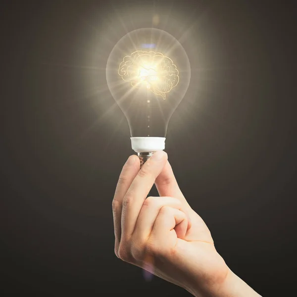 Close up of hand holding illuminated light bulb with brain on dark background. Brainstorming concept — Stock Photo, Image